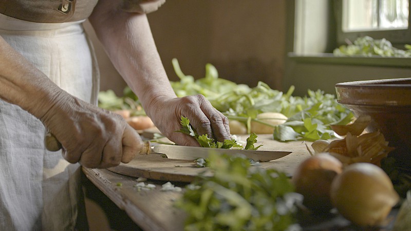 Frische Kräuter werden auf einem Holztisch geschnitten.