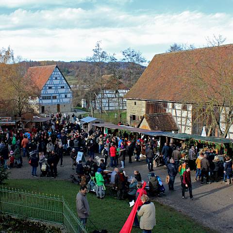Besucher:innen auf dem Vorweihnachtsmarkt aus einem Fenster der Scheune aus Bühlenzimmern betrachtet
