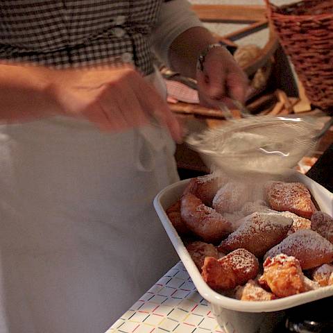 Frisches Schmalzgebäck wird mit Puderzucker bestreut